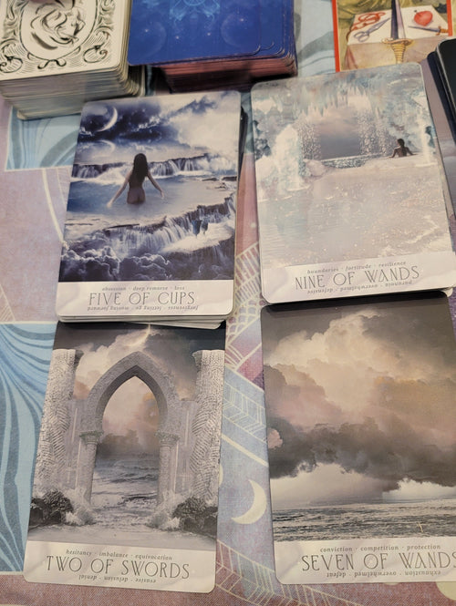 Collection of tarot cards with various designs and text on a textured surface.